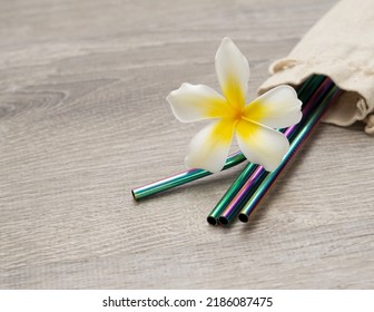 White And Yellow Plumeria Blossom With Colorful Reusable Metal Straws On Light Wood Background Concept Of Responsible Travel And Sustainability 