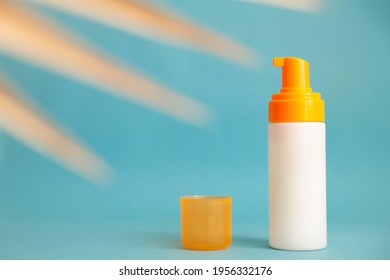 White And Yellow Sunscreen Bottle With Cream Or Lotion On The Aqua Blue Background With Palm Branch. Empty Bottle Mockup. Spf Sun Protection, Summer Skin Care.