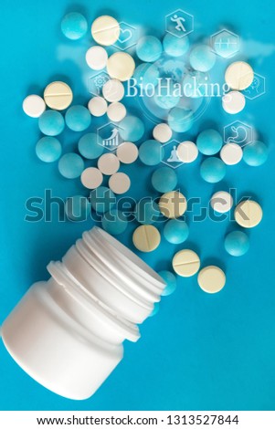 White and yellowWhite  round pills are poured against a blue white plastic pill background. view from above. drug. concept of biohacking