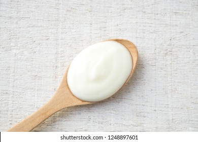 White Yogurt On Wooden Spoon On White Wood Background.