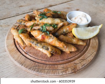 Whitebait, Small Fried Fish Served On A Wooden Rustic Platter And Wooden Table With A Dip And Lemon.