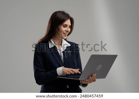 A whitecollar worker in a blazer, using technology on her laptop with a smile