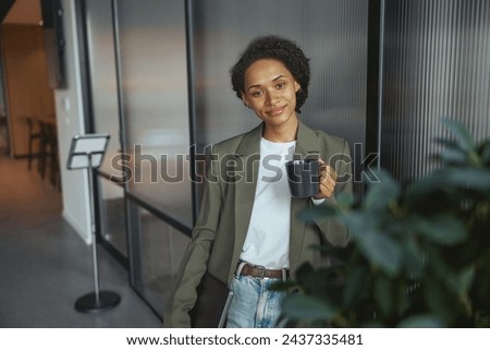 A whitecollar worker is standing in a hallway holding a cup of coffee