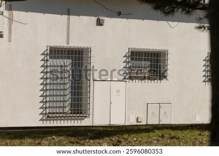A whitecolored building with bars secured on the windows and an entrance door that stands out against the architecture