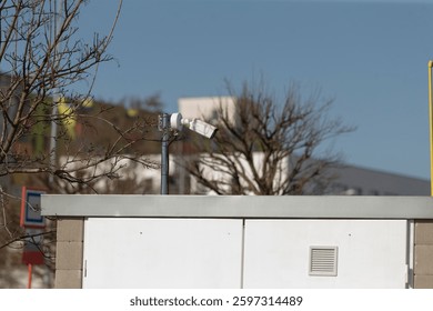 A whitecolored building featuring a camera positioned on its rooftop observing the surroundings, ensuring security and monitoring activities