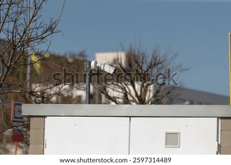 A whitecolored building featuring a camera positioned on its rooftop observing the surroundings, ensuring security and monitoring activities