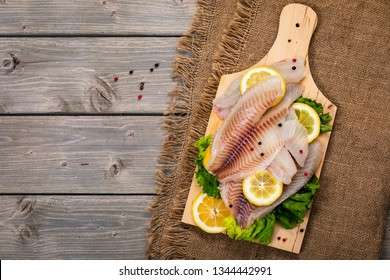 Whitefish Tilapia Fish Raw Fresh Fillet Ready To Cook On Wooden Background. Selective Focus.