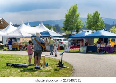 Whitehorse, Yukon Territory, Canada - Jun 30, 2022: Father with son busking at the local Fireweed Community Market during Canada Day long weekend