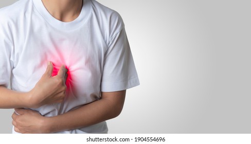 A white-robed Asian woman showed chest pain by putting her hand on the center of her chest. health issues, an empty space on the right-hand side of the image to insert text. - Shutterstock ID 1904554696