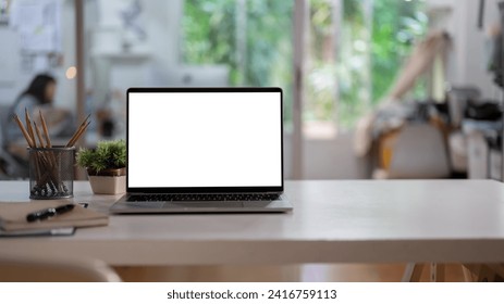 A white-screen laptop computer mockup and accessories on a white desk in a modern office. Office workspace - Powered by Shutterstock