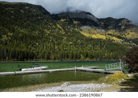 Whiteswan Lake in Provincial Park, Kootenay Rockies, British Columbia, Canada. View of a boat in a dock on green water, mountain forest on a cloudy autumn day
