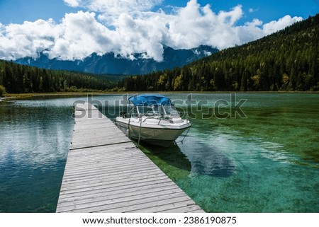 Whiteswan Lake in Provincial Park, Kootenay Rockies, British Columbia, Canada. View of a boat in a dock on green water, mountain forest on a cloudy autumn day