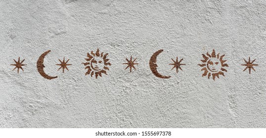 Whitewashed wall decorated with a horizontal sequence of suns, stars and moons.