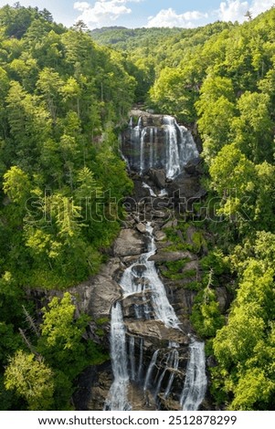 Whitewater Falls with falling down clear water from rocky boulders between green lush woods in Nantahala National Forest, North Carolina, USA