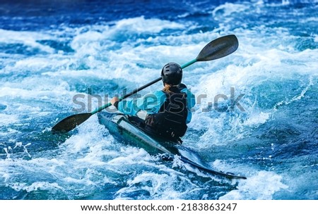 Whitewater kayaking, extreme sport rafting. Back view young woman in kayak sails mountain river.