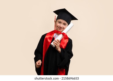 Whizz kid 9-11 year wearing graduation cap and ceremony robe Pressed Paper Certificate of Education to Cheek. Еlementary school graduate boy with certificate diploma tied with red ribbon in studio. - Shutterstock ID 2158696653
