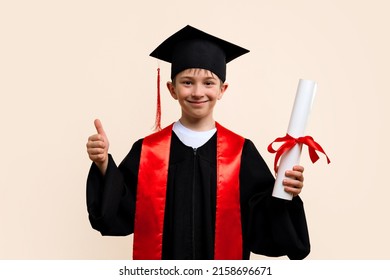 Whizz kid 9-11 year wearing graduation cap and ceremony robe shows thumb up, approval sign. Еlementary school graduate boy with certificate diploma tied with red ribbon in studio. - Shutterstock ID 2158696671