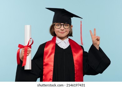 Whizz kid girl 9-11 year girl wearing graduation cap, round eyeglasses and ceremony robe with certificate diploma on blue background. Child  have positive emotions, showing V-sign and peace sign