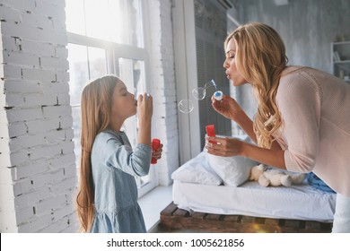 Who Got Bigger? Mother And Daughter Blowing Soap Bubbles While Spending Time At Home