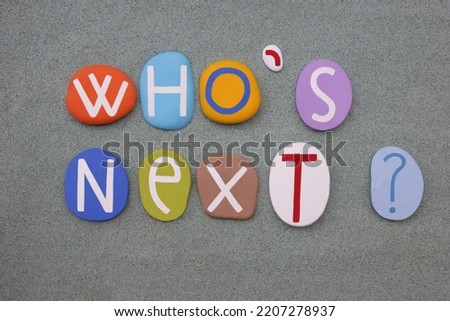Who is next, creative question composed with multi colored stone letters over green sand