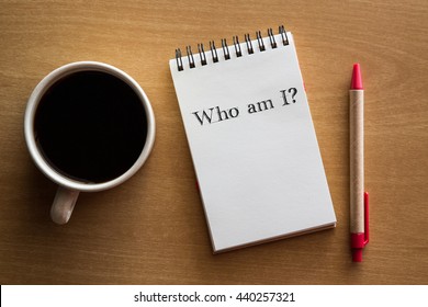 Who Am I? A Question In Handwriting On A Notebook With Cup Of Coffee