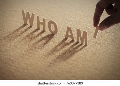 WHO AM I wood word on compressed or corkboard with human's finger at I letter. - Shutterstock ID 763379383