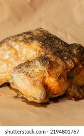 Whole Chicken Coated In Mixed Herbs Roasted In An Oven. On A Brown Paper Background