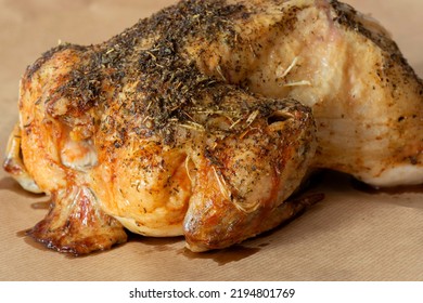 Whole Chicken Coated In Mixed Herbs Roasted In An Oven. On A Brown Paper Background