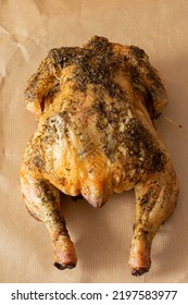 Whole Chicken Coated In Mixed Herbs Roasted In An Oven. On A Brown Paper Background