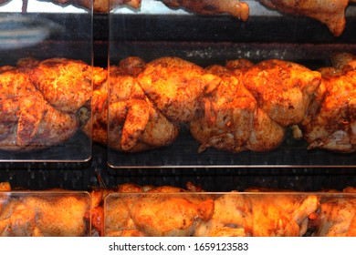 Whole Chickens Being Roasted In A Rotisserie Oven Behind Clear Perspex Covers