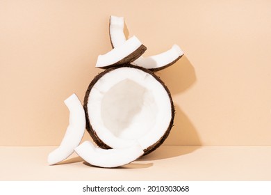 Whole coconut and pieces of coconut on beige background, top view. Minimalism