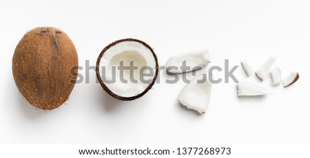 Whole coconut and pieces of coconut on white background, top view