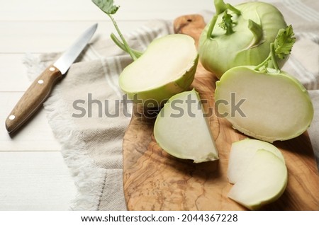 Whole and cut kohlrabi plants on white wooden table
