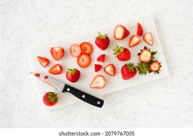 Whole, cut, sliced, quartered and halved strawberries on white marble chopping board over marble background with copy space. Top view. Horizontal Version. - Powered by Shutterstock