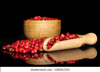 Lot Of Whole Dry Peruvian Pink Pepper In A Wooden Bowl With Wooden Scoop Isolated On Black Glass