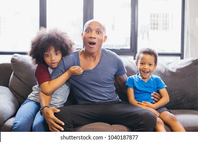 Whole Family Of African American Watching And Staring Horror Movie On TV At Home. They Are Getting Frightened And Scared