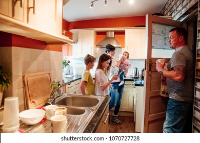 A Whole Family Are Busy In The Kitchen Of Their Home.