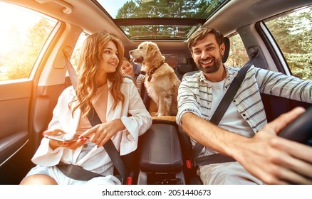 The whole family is driving for the weekend. Mom and Dad with their daughter and a Labrador dog are sitting in the car. Leisure, travel, tourism. - Shutterstock ID 2051440673