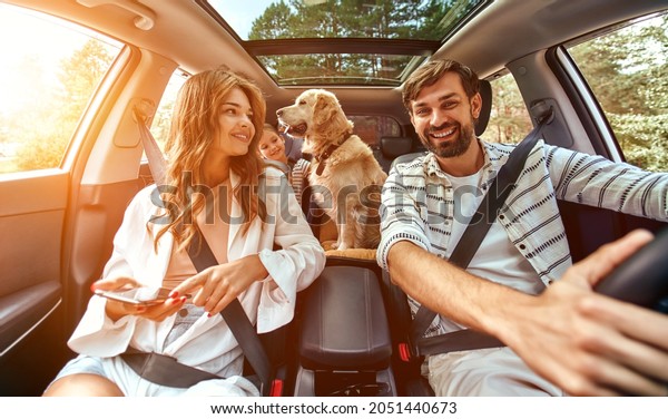 The whole family is driving for the\
weekend. Mom and Dad with their daughter and a Labrador dog are\
sitting in the car. Leisure, travel,\
tourism.