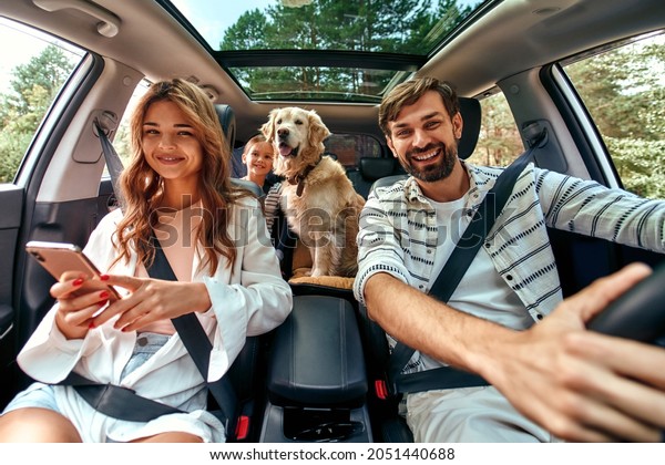 The whole family is driving for the\
weekend. Mom and Dad with their daughter and a Labrador dog are\
sitting in the car. Leisure, travel,\
tourism.