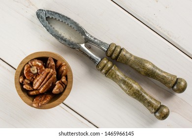 Lot Of Whole Fresh Brown Pecan Nut Half In A Wooden Bowl With Vintage Nutcracker Flatlay On White Wood