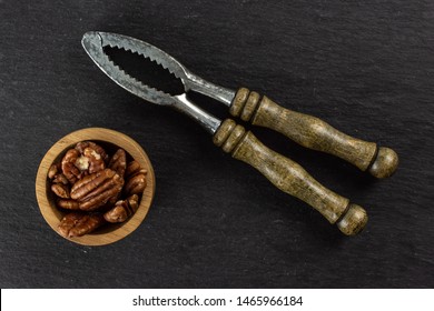 Lot Of Whole Fresh Brown Pecan Nut Half In A Wooden Bowl With Vintage Nutcracker Flatlay On Grey Stone