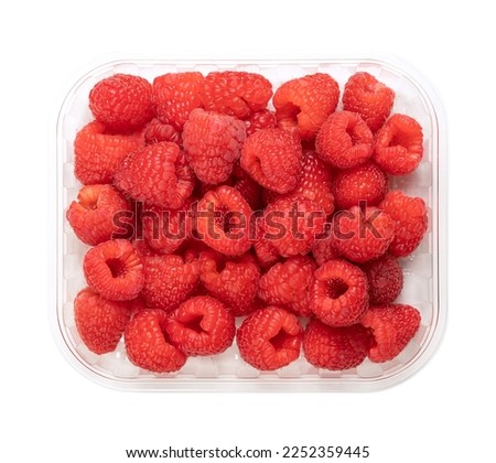 Whole fresh raspberries, in a clear plastic punnet, from above. Ripe, red and sweet fruits of Rubus idaeus, the cultivated European raspberry. Organic and vegan fruits. Isolated, close-up, food photo.