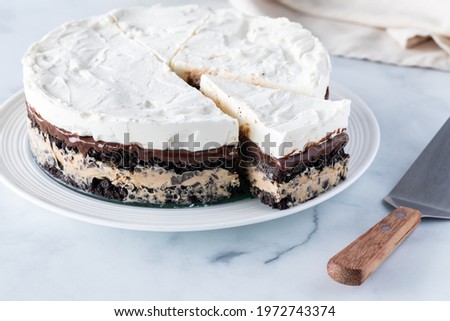 A whole frozen layered pie including mocha ice cream and crushed cookie wafers, with one slice cut out.