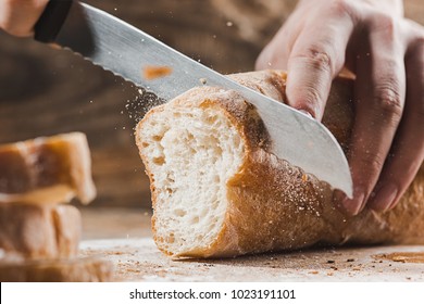 Whole grain bread put on kitchen wood plate with a chef holding gold knife for cut. Fresh bread on table close-up. Fresh bread on the kitchen table The healthy eating and traditional bakery concept - Shutterstock ID 1023191101