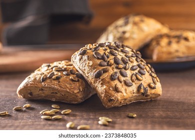 Whole grain bun with pumpkin seeds on the wooden table. - Shutterstock ID 2373848035