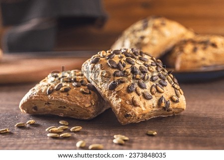 Whole grain bun with pumpkin seeds on the wooden table.