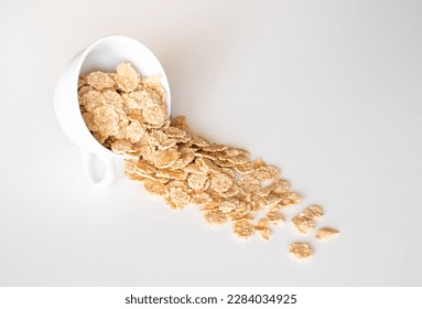 Whole grain cereal flakes in bowl. Wholegrain breakfast cereals isolated on a white background