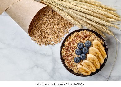 Whole Grain Oatmeal With Blueberries And Banana Slices In A Dark Bowl