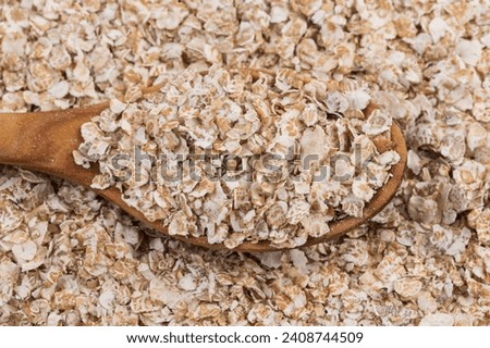 Whole grain, rolled oats flakes with wooden spoon